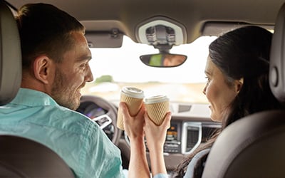 Två personer som skålar med kaffe i bilen